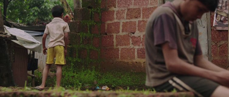 two young boys sitting on the ground in front of a brick building