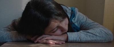 a woman sitting at a table with her head on her hands