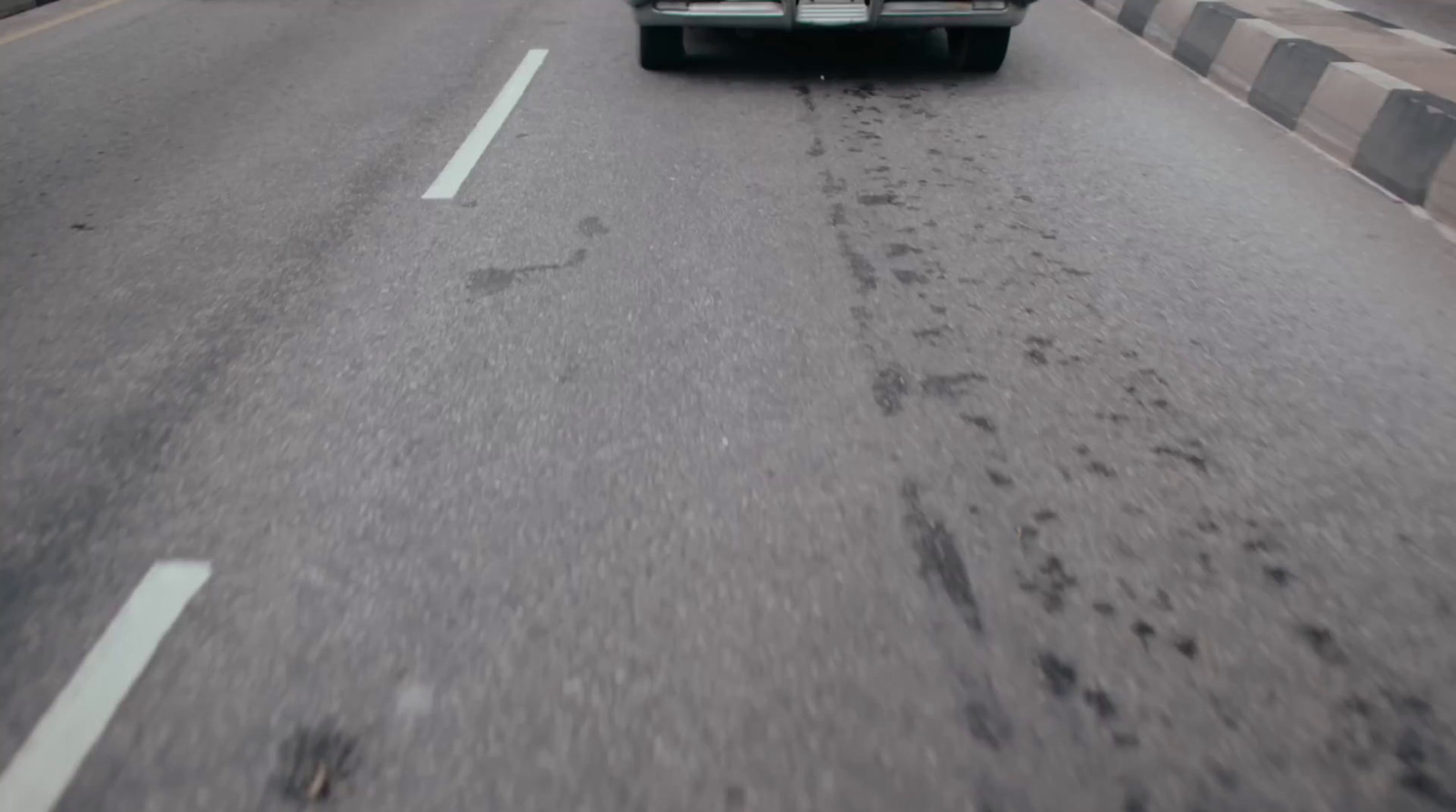 a truck driving down a street next to a tall building