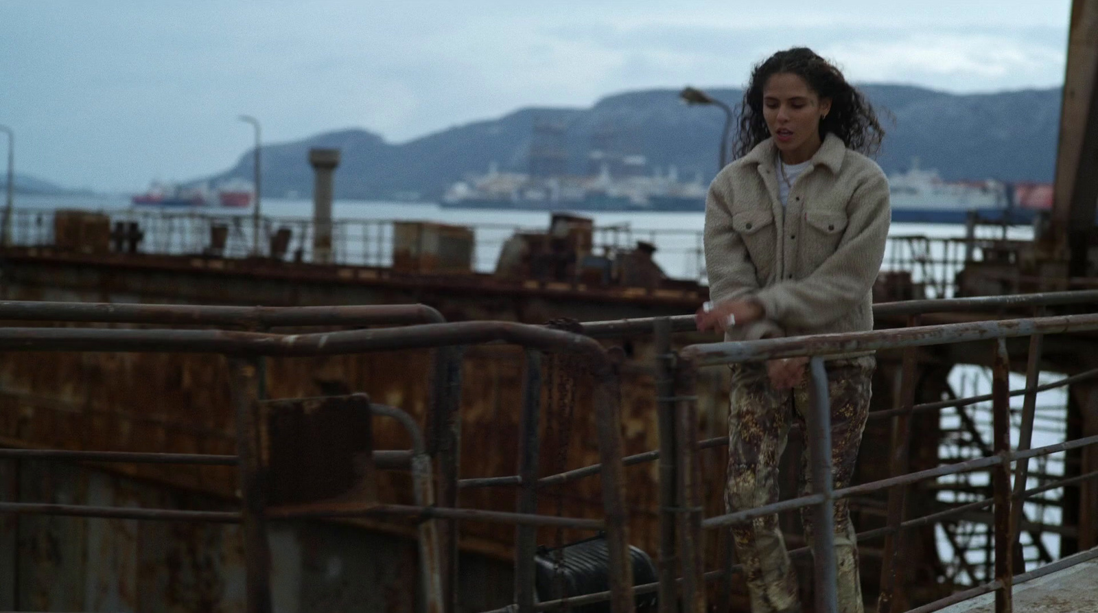 a woman standing on top of a rusty bridge