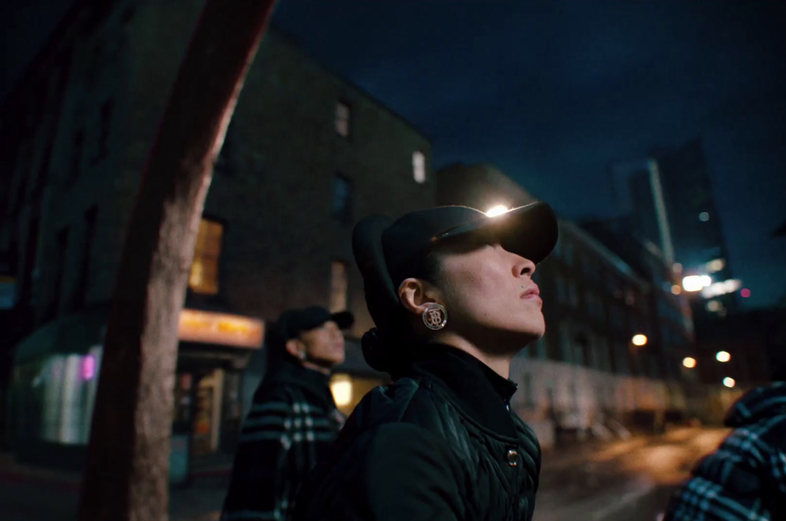 a woman wearing a hat and glasses standing on the side of a street