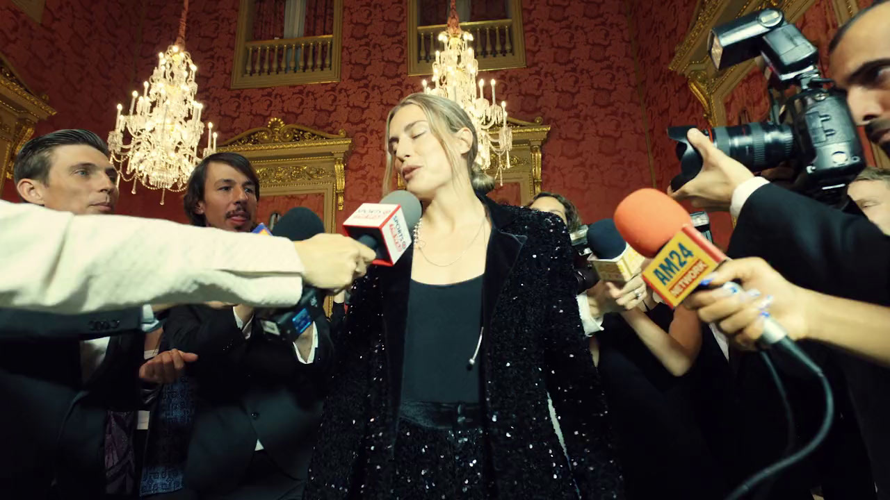 a woman in a black dress surrounded by reporters