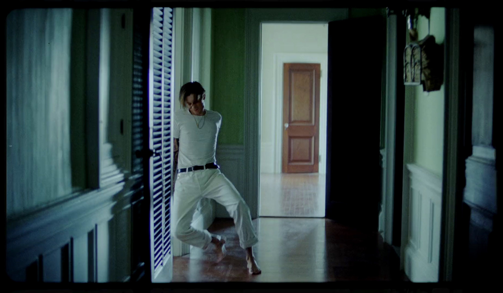 a woman in a white outfit is dancing in a hallway