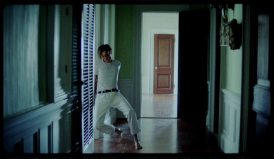 a woman in a white outfit is dancing in a hallway