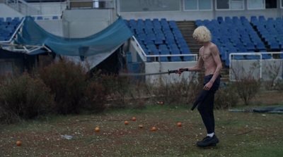 a shirtless man holding a gun in a field