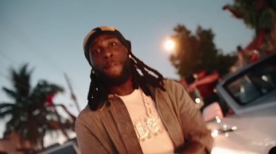 a man with dreadlocks standing in front of a car