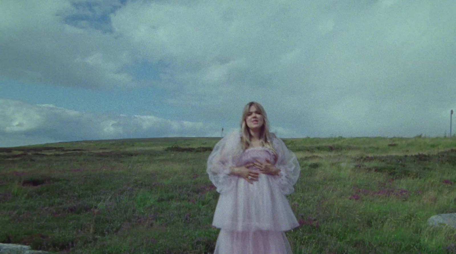 a woman in a pink dress standing in a field