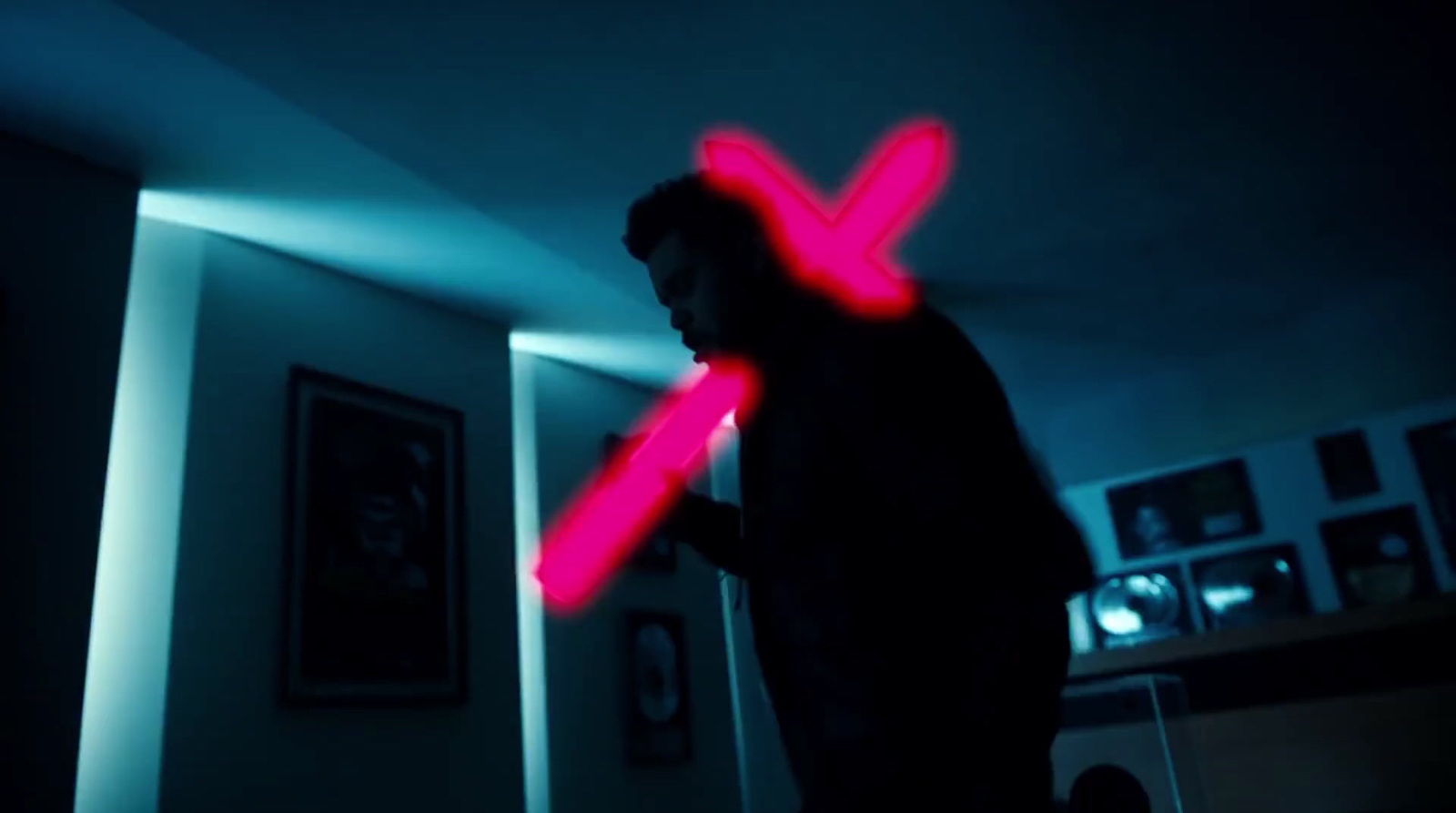 a man standing in a dark room with a red x on his chest