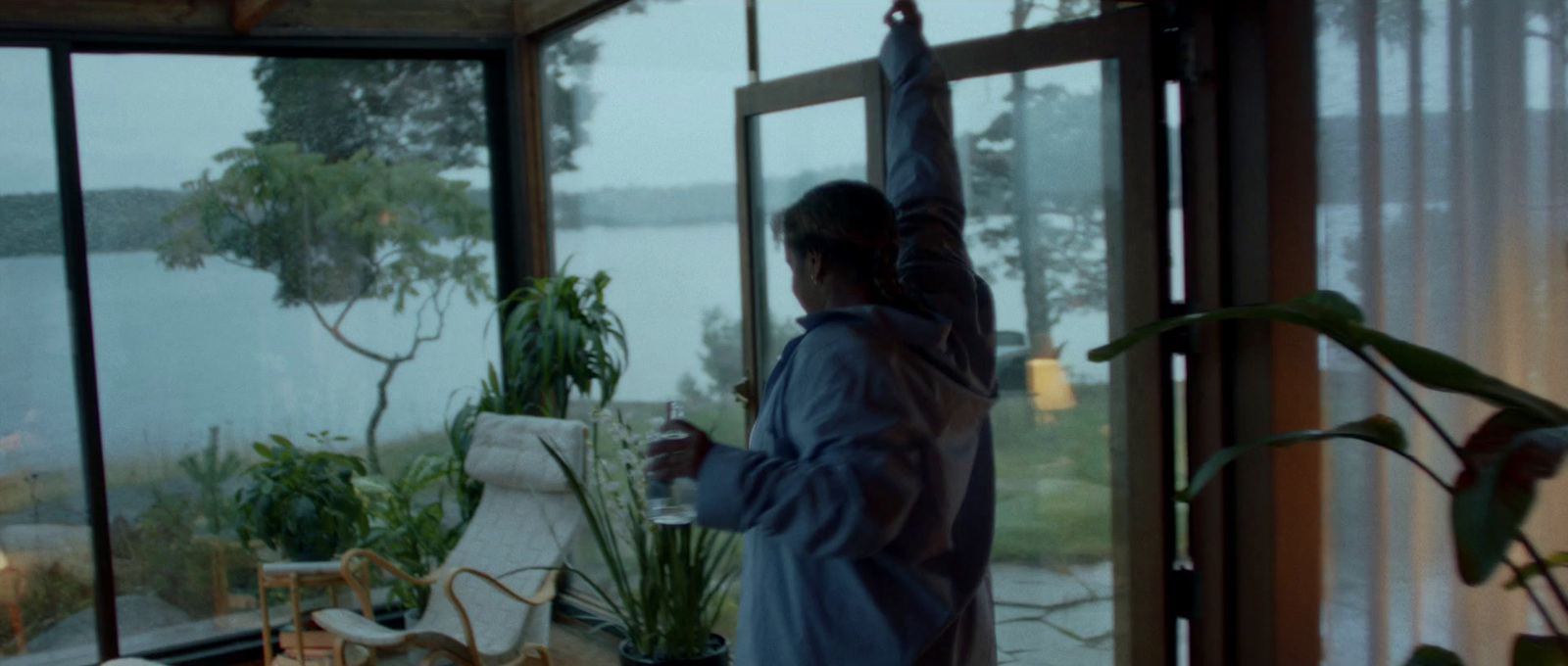 a woman standing in front of a window next to a plant