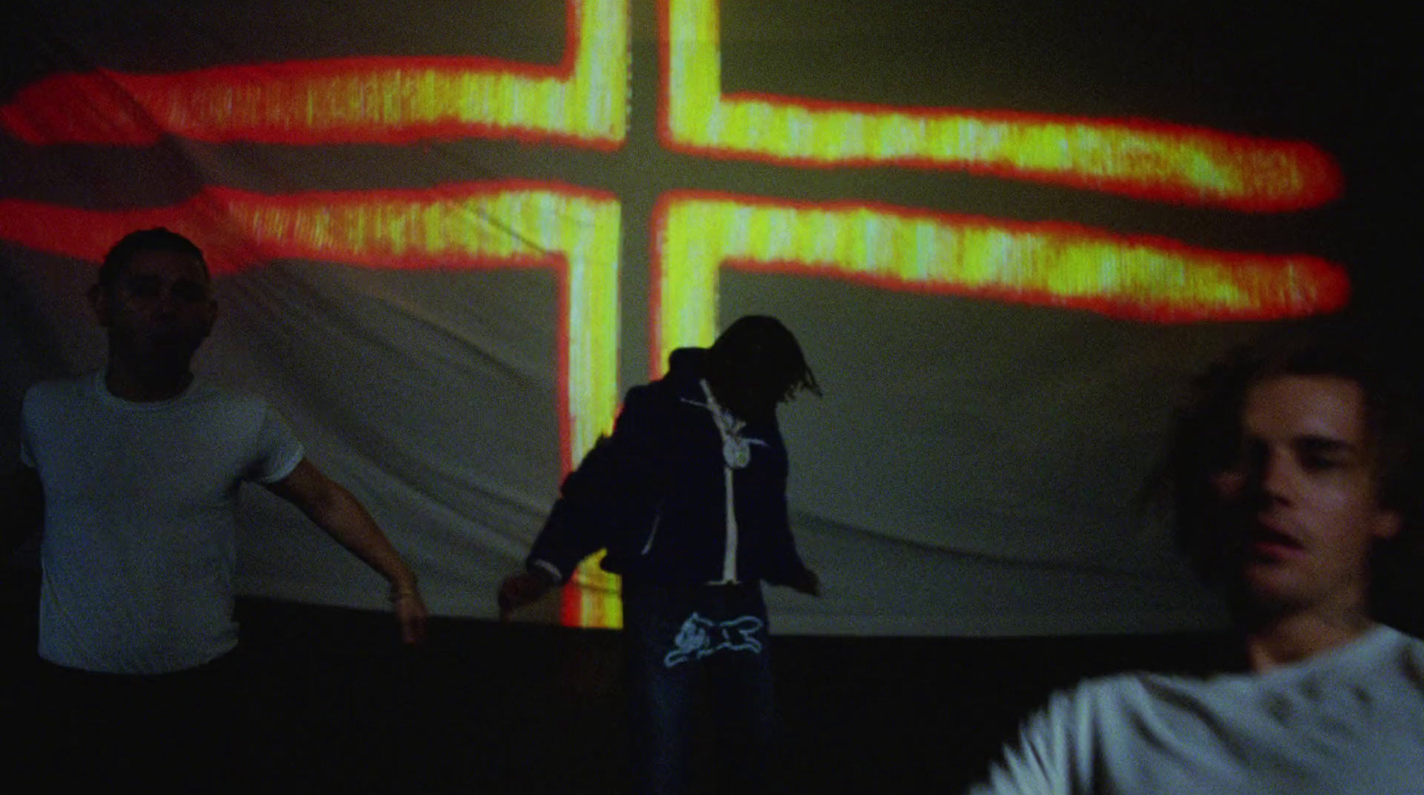 two men standing in front of a cross on a wall