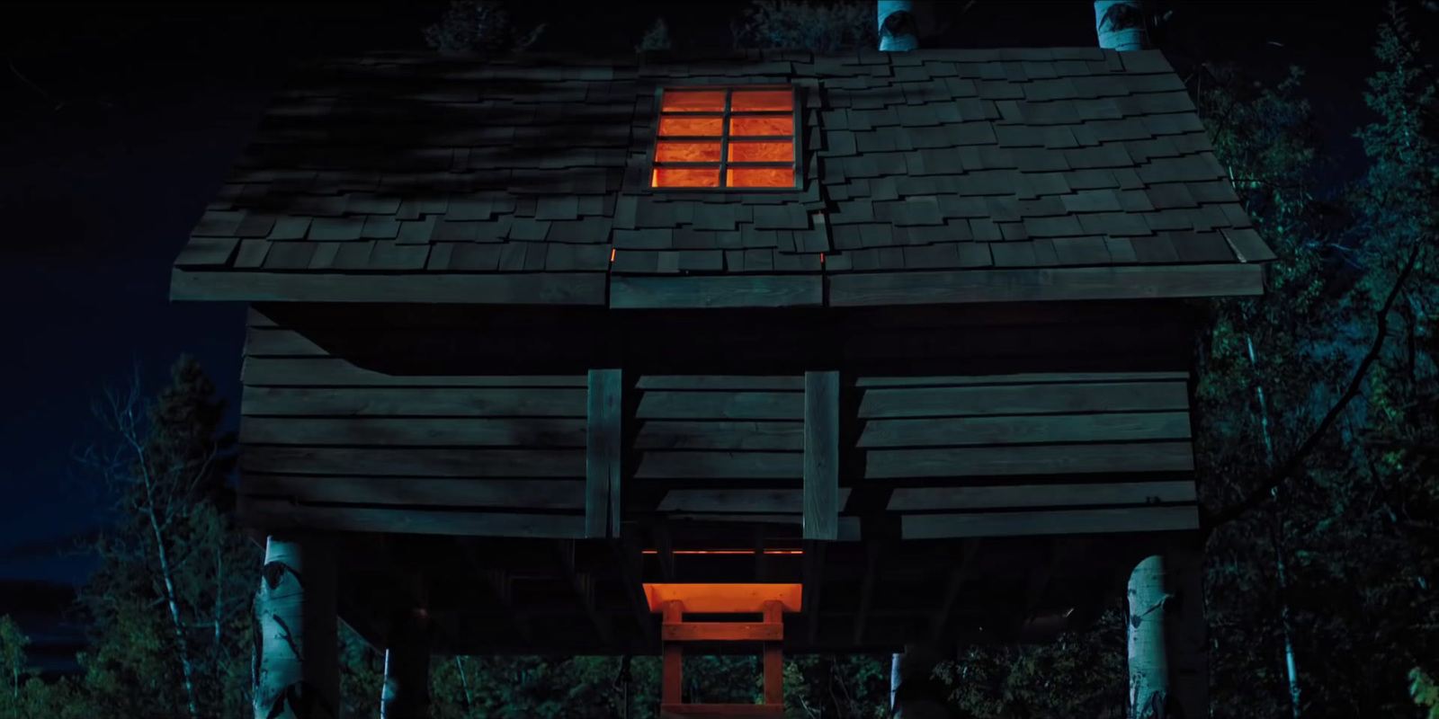 a small wooden cabin with a lit window at night