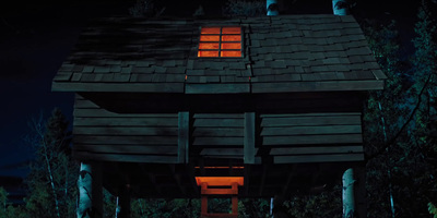 a small wooden cabin with a lit window at night