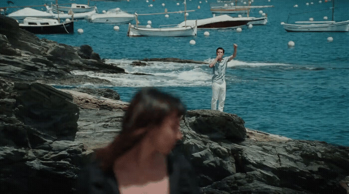 a woman standing on a rock next to a body of water