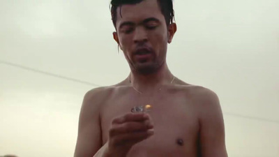 a shirtless man holding a piece of food in his hand