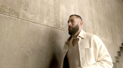 a man with a beard standing next to a wall