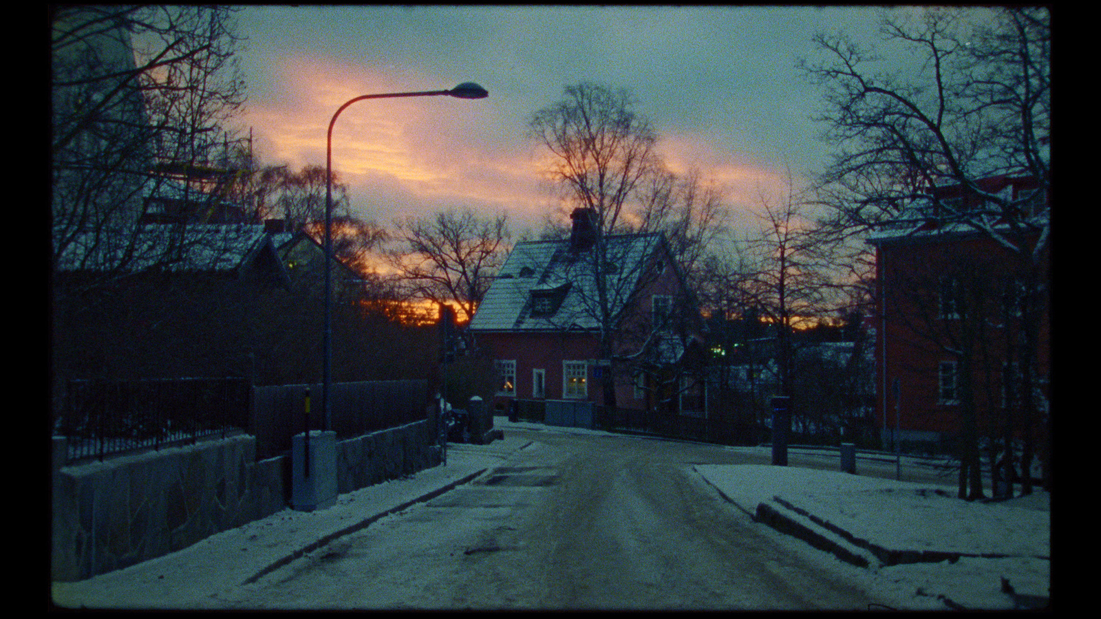 a street with snow on the ground and a street light in the distance