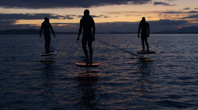 three people standing on surfboards in the water