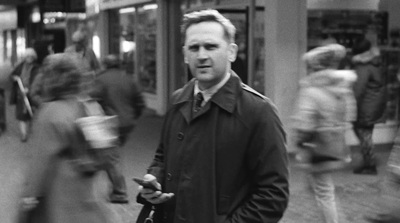 a black and white photo of a man in a trench coat