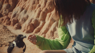 a woman sitting next to a small bird