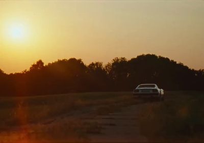 a car driving down a dirt road at sunset