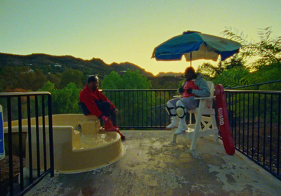 two people sitting under an umbrella on a balcony