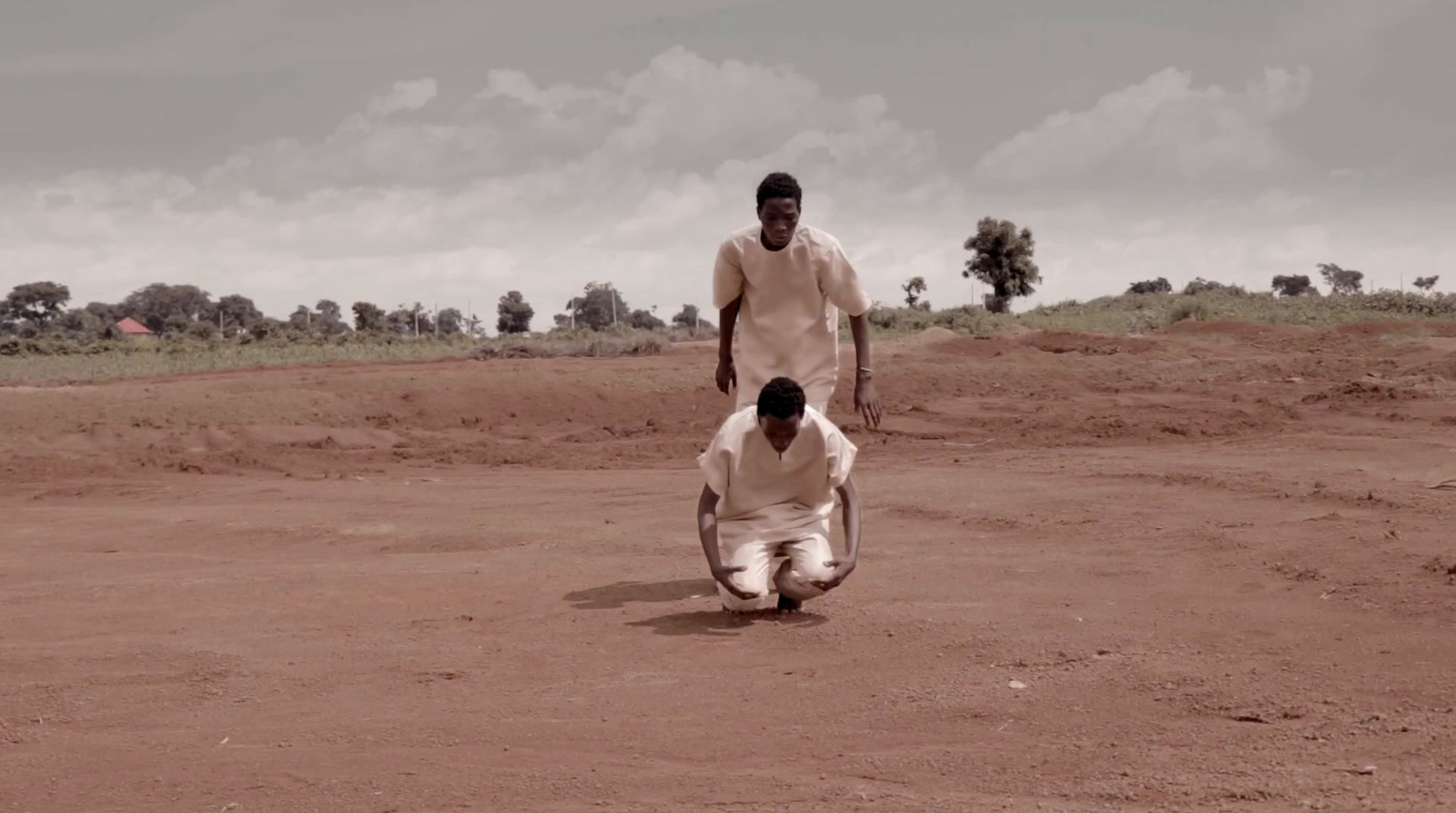 a couple of men standing on top of a dirt field