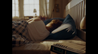 a person sleeping on a bed with a alarm clock