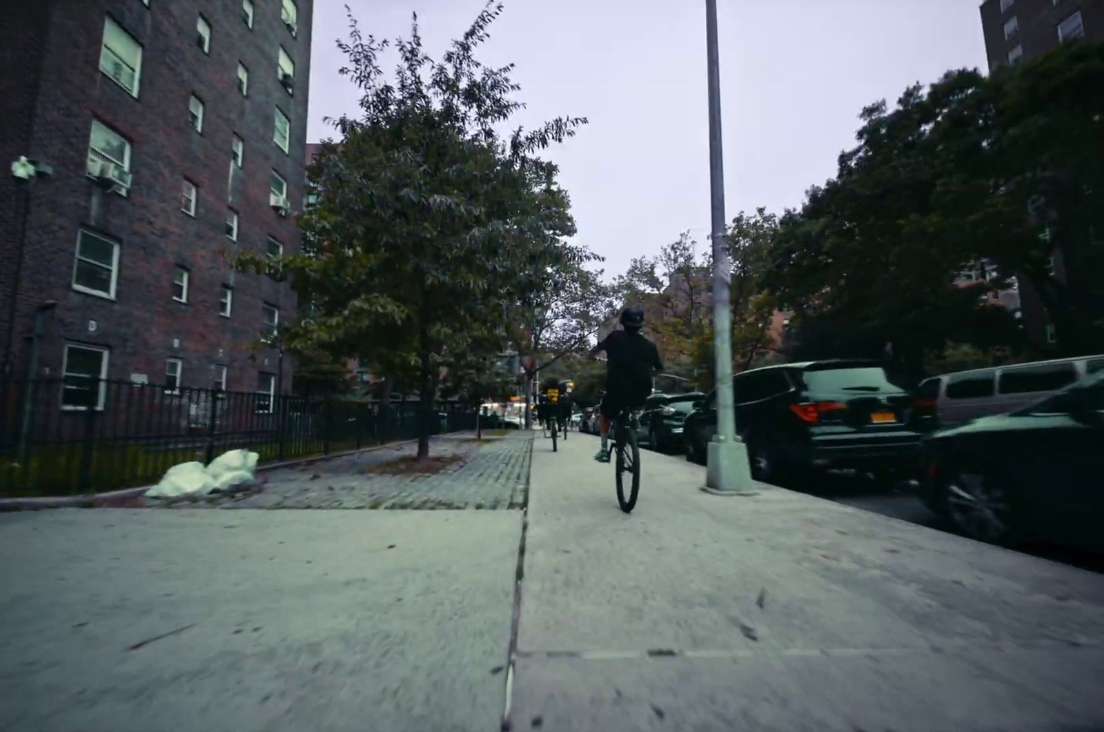 a man riding a bike down a street next to tall buildings