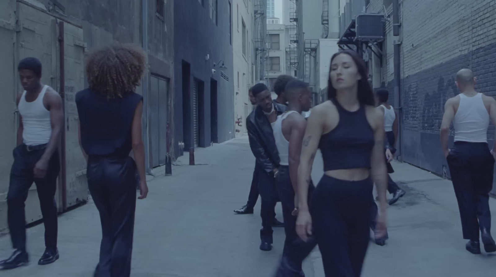 a group of people walking down a street next to tall buildings