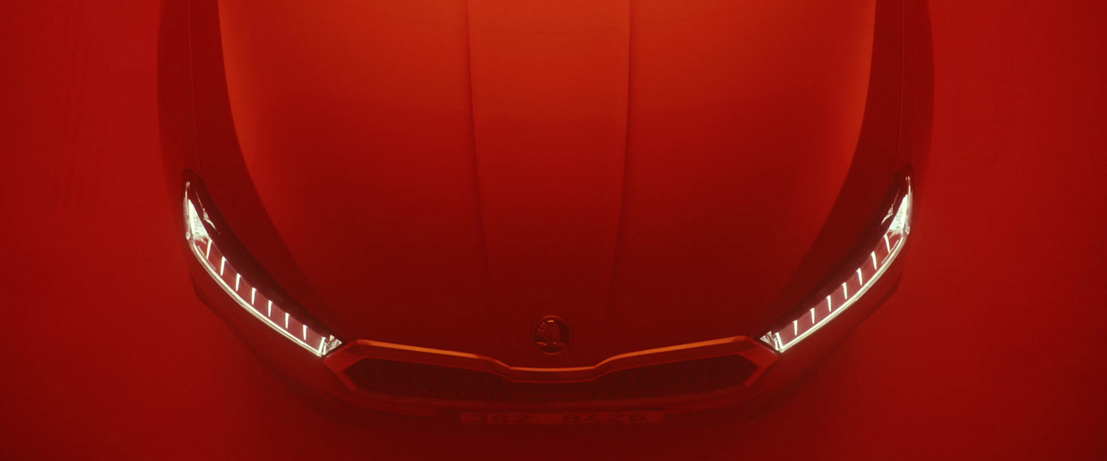 the front of a red sports car with its lights on