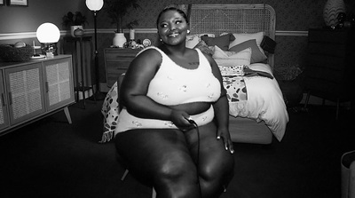 a black and white photo of a woman sitting on a bed