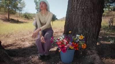 a woman sitting on the ground next to a tree