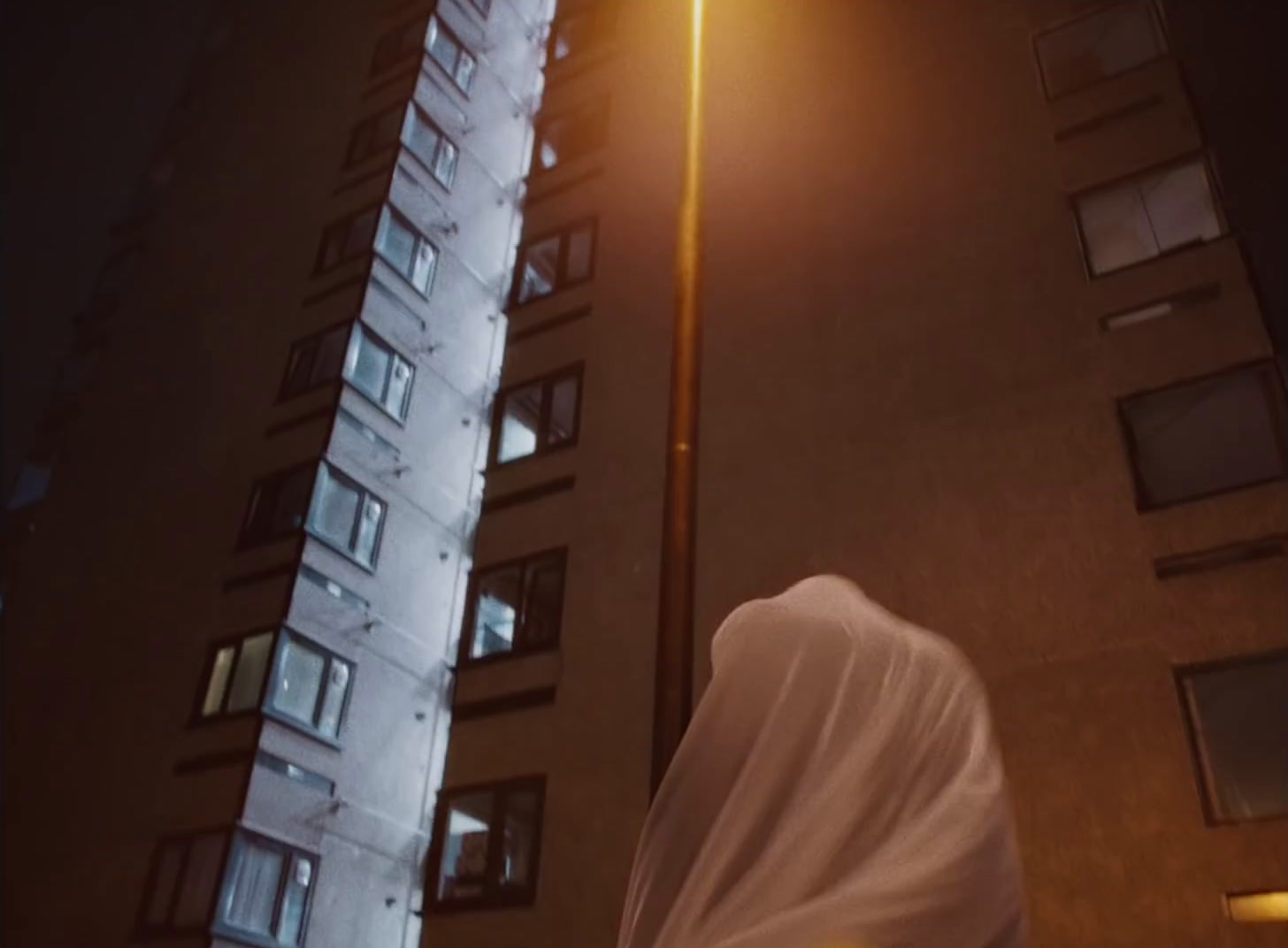 a woman in a white veil standing in front of a tall building