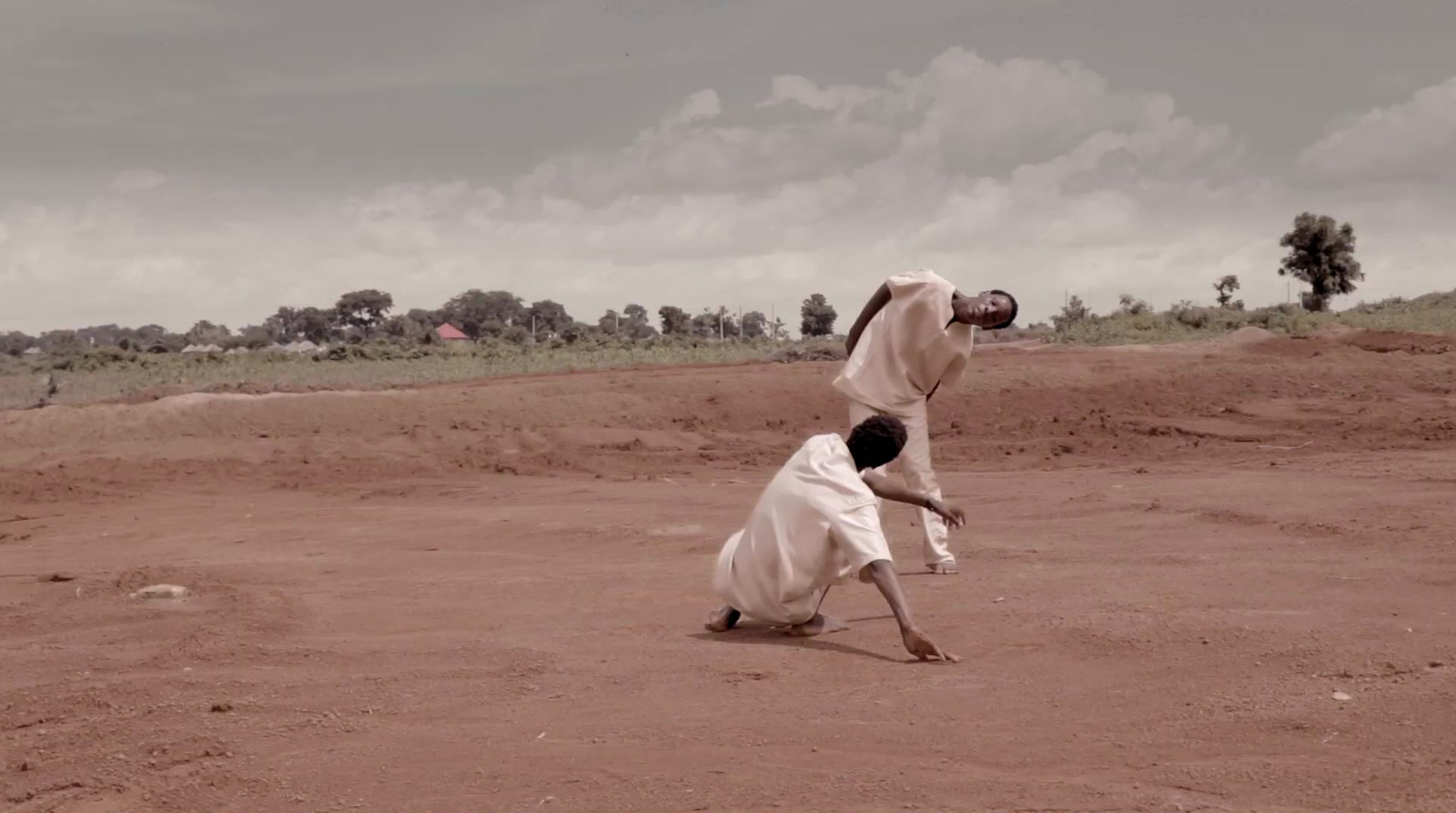 a couple of men standing on top of a dirt field