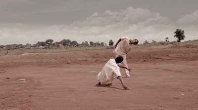 a couple of men standing on top of a dirt field