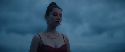 a woman in a red dress standing in front of a cloudy sky