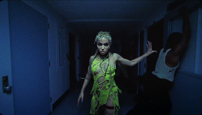 a woman in a neon green dress walking down a hallway