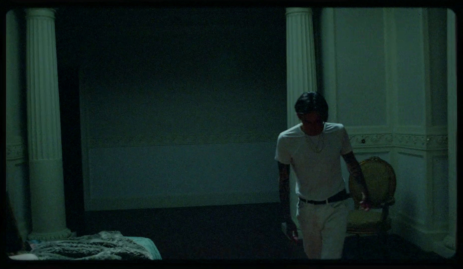 a man standing in a dark room next to a bed