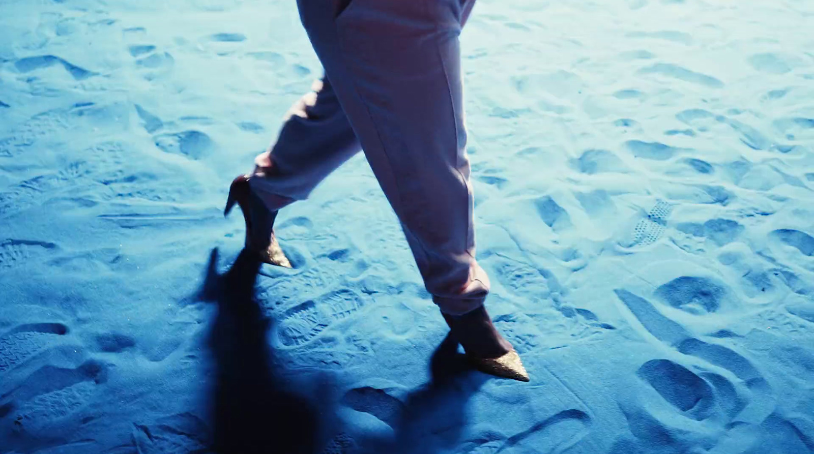 a woman in high heels walking on a beach