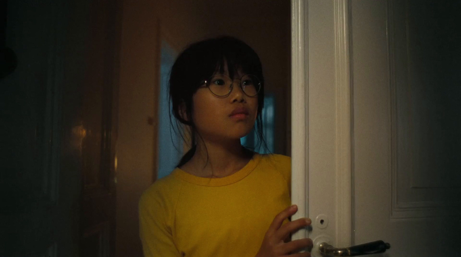 a girl in a yellow shirt holding a door handle