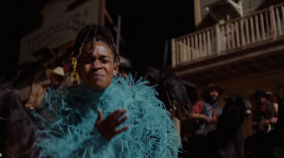 a woman in a blue feather coat standing in front of a crowd