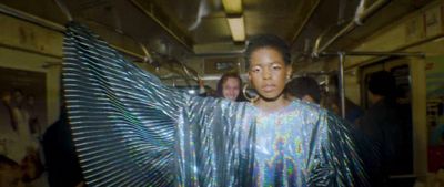 a woman in a shiny dress standing on a subway