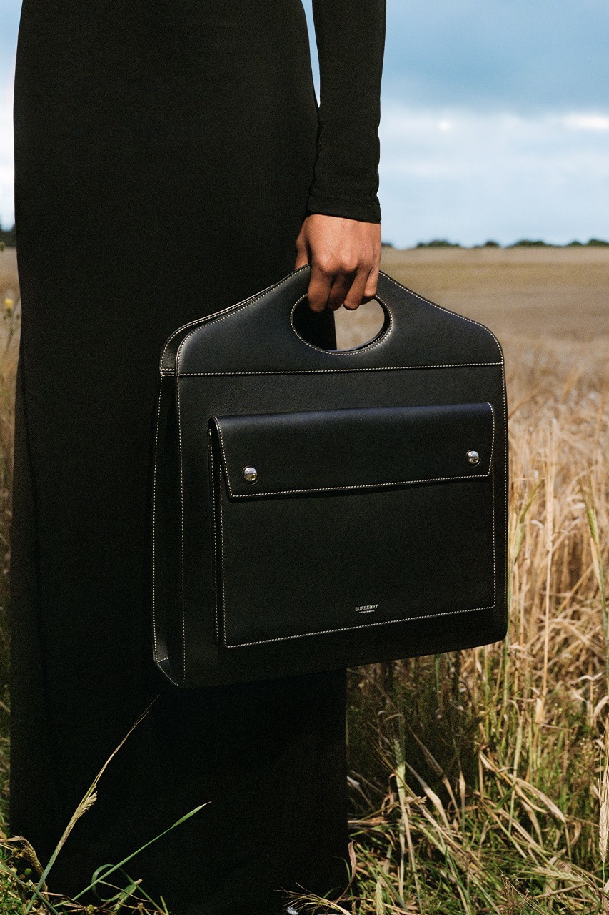 a person holding a black briefcase in a field