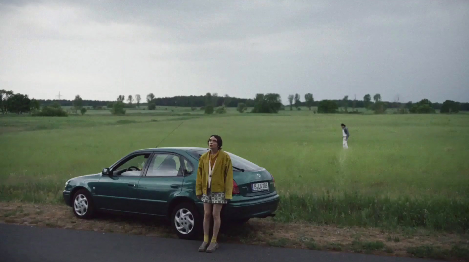 a woman standing next to a car on a road