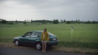 a woman standing next to a car on a road