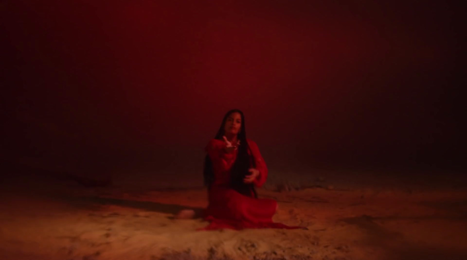 a woman in a red dress sitting on the ground