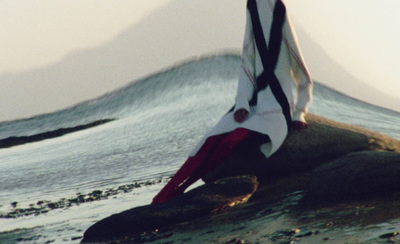 a person sitting on a rock with a surfboard