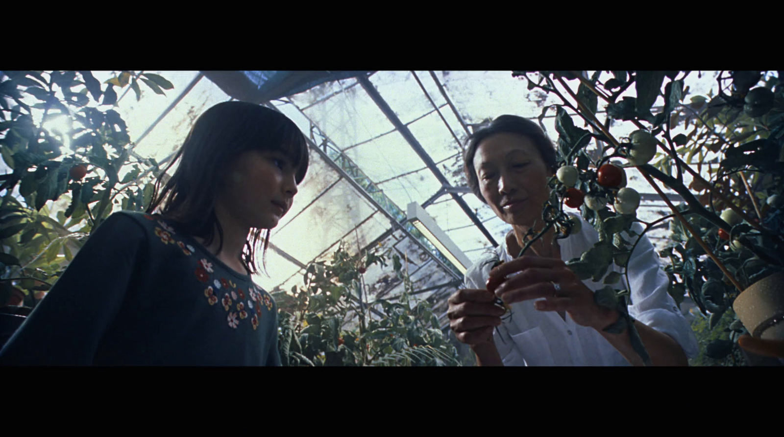 two women standing next to each other in a greenhouse