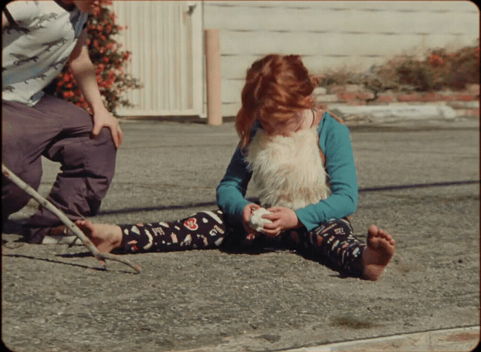 a young girl sitting on the ground next to a man