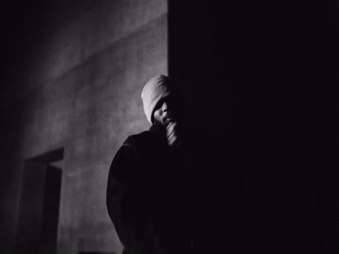 a man in a white turban standing in a dark room